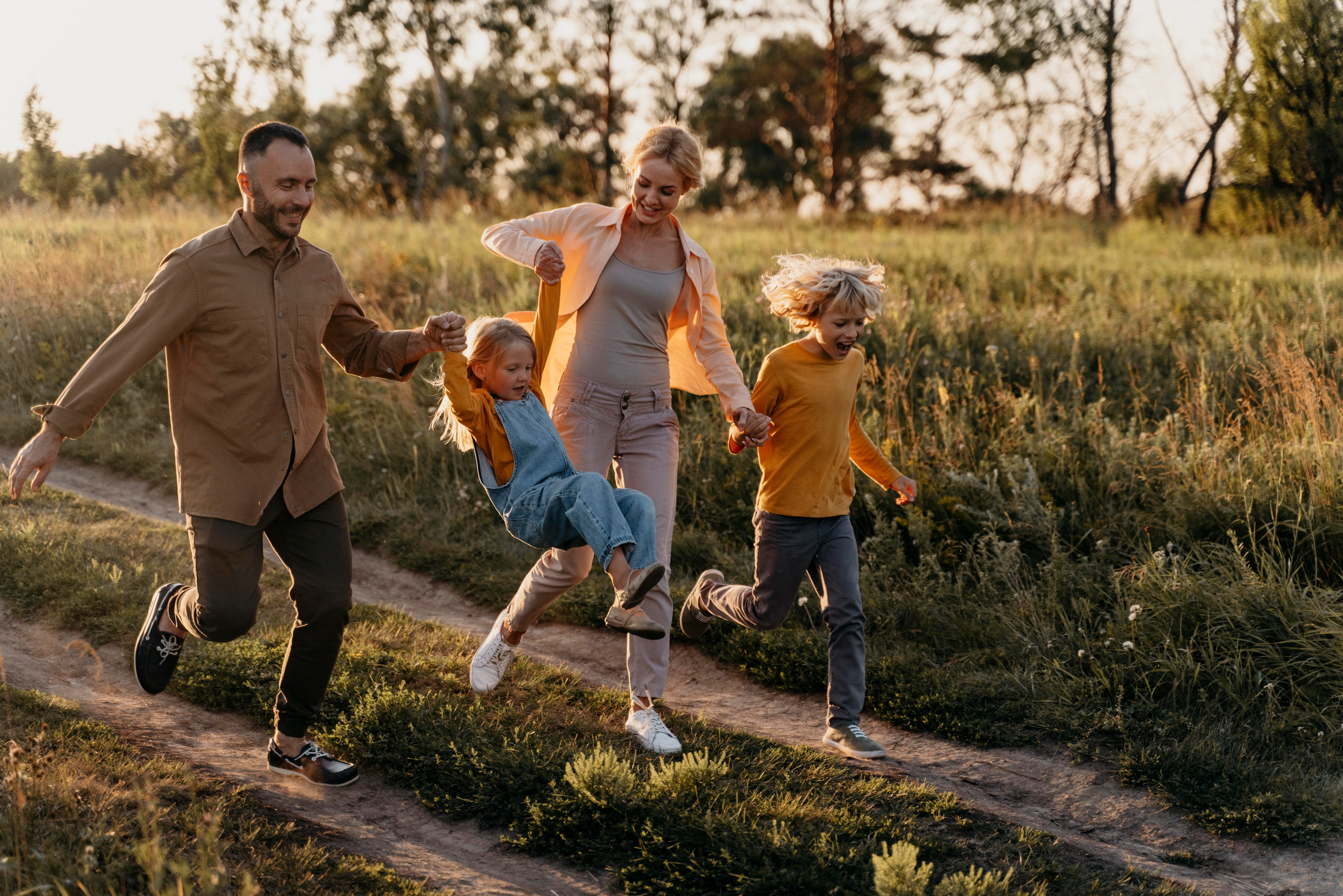 Familia corriendo por la pradera disfrutando de la compañía del resto